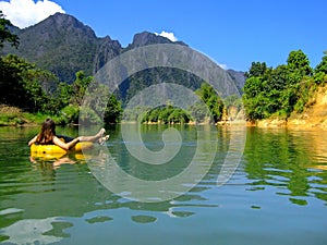 Tourist going down Nam Song River in a tube surrounded by karst