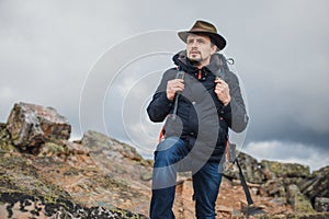 Tourist in green hat, blue jacket walking on the mountain