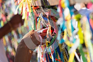 Tourist hands tying souvenir ribbons on the railing of the Senhor do Bonfim church in the city of Salvador, Bahia