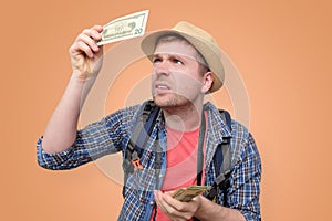 Tourist in hat holds dollar bank note checking it