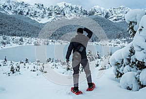 Tourist hiker with crampons looking at mountains in snow.