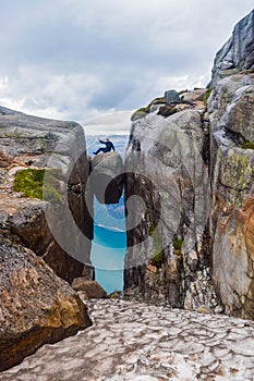 The tourist hiker man sitting on top of Kjeragbolten - the most dangerous stone in the world. Norway