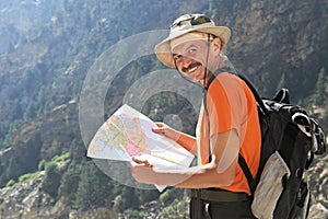 Tourist hiker with map in mountains