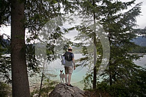 Tourist hiking on alpine lake with dog