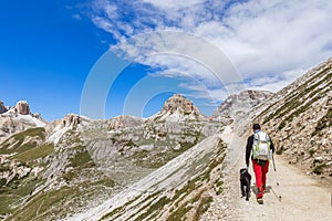 Tourist with his black Labrador  walking on a pass to the mountain hut