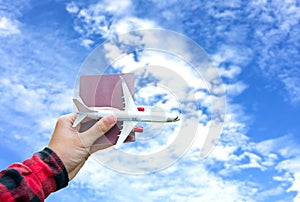 Tourist holding airplane flight travel and passport traveller fly travelling citizenship air on blue sky background.