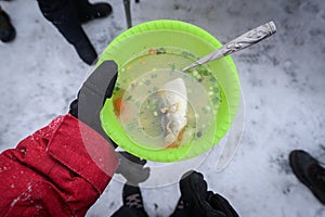 Tourist holding a hot of Omul fish soup in hand during picnic in lake Baikal, Russia.