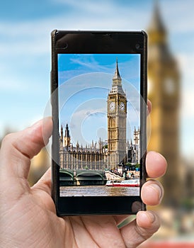 Tourist holds smartphone in hand and photographing Big Ben in London