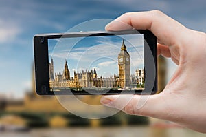 Tourist holds smartphone in hand and photographing Big Ben in London