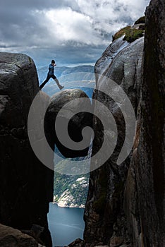 Tourist jumps on giant boulder, Visiting Norway Kjeragbolten located south of Lysefjorden