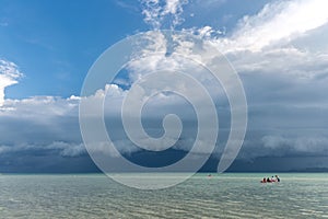 Tourist kayaking in the emerald Thailand sea at the cloudy blue sky background