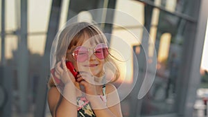Tourist kid girl wearing stylish sunglasses use phone. Child using smartphone for call talk. Tourism