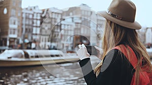 Tourist lady takes photos of old architecture. Girl with long hair and red backpack enjoying amazing city scenery. 4K.