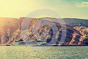 Tourist liner at the coast behind a background of rocks in the fjords of the Gulf of Oman