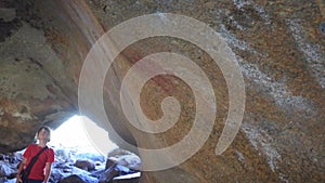 Tourist looking at Aboriginal australian indigenous rock painting in Mulkas Cave Hyden Western Australia