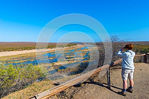 Tourist looking at panorama with binocular from viewpoint over the Olifants river, scenic and colorful landscape with wildlife in