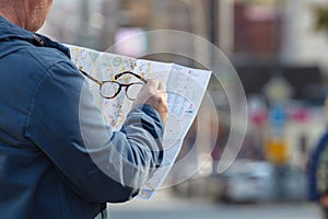 Tourist looking at the paper map instead phone. Positive emotion