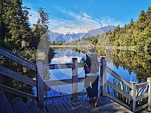 A tourist looking at the reflection of Mount Cook at Lake Matheson on the South Island of New Zealand