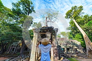 Tourist looking at Ta Prohm famous jungle tree roots embracing Angkor temples, revenge of nature against human buildings, travel