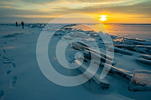 Tourist looking to beautiful landscape of Uzury bay with ice hummock rising above the frozen lake of Baikal at sunrise.