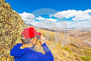 A tourist looks through binoculars on a mountain landscape