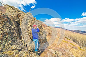 A tourist looks through binoculars on a mountain landscape