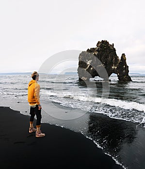 Tourist looks at the Hvitserkur basalt stack in northern Iceland