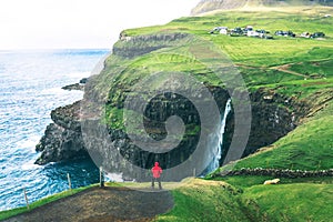 Tourist looks at the Mulafossur waterfall near Gasadalur on Faroe Islands