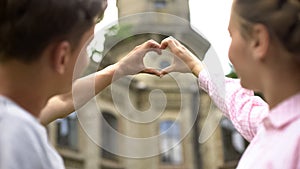 Tourist lovers making heart shape with hands against showplace, adventure photo