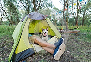 Tourist lying in tent with dog, camping in autumn nature