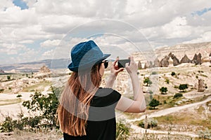 A tourist makes a photo on the phone in memory of a beautiful view of the hills in Cappadocia in Turkey. Travel, tourism