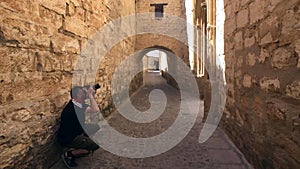 Tourist making photos in, medieval neighborhood, alleyway with stone arch, Baeza, Patrimony of the Humanity, Andalu