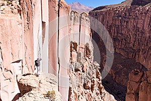 Tourist man adventurer backpacker standing above deep canyon, Bolivia