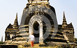 Tourist Man with camera is walking in to an ancient ruined stupa in Ayutthaya Historical Park, Thailand, Travelling Thailand Back