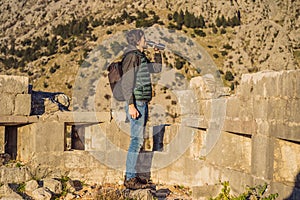 tourist man enjoying a view of Kotor Bay, Montenegro. Kotor Old Town Ladder of Kotor Fortress Hiking Trail. Aerial drone