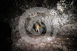 Tourist man explore the lava cave with flashlight in Maui, Hawaii.