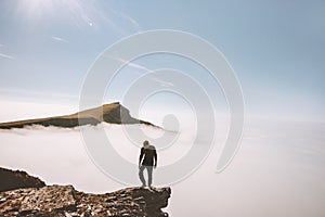 Tourist man exploring mountains over clouds active adventure