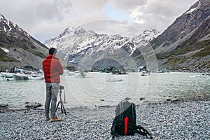 Tourist man with jacket takes photo of Mount Cook by DSLR camera with tripod