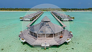 Tourist man at the overwater villas at the beautiful tropical island resort. Sunny day. Aerial photo