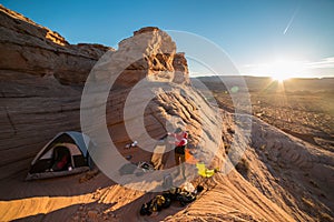 Tourist man prepearing campground with a ten in mountain desert at sunset time. Travel lifestyle photo