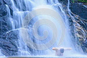 Tourist man relaxing under flowing waterfall nature. Nature Therapy.