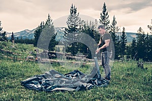 Tourist man setting up intake tent in the forest.