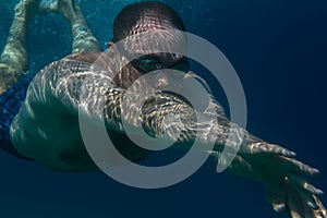 Tourist man in swimming sports glasses swimming underwater in the Aegean Sea on the coast of Sithonia Peninsula