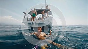 Tourist man swims for yacht. Split with underwater, real shoot. Slow motion