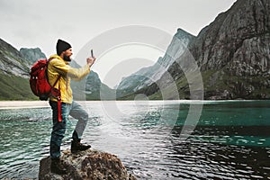 Tourist Man taking selfie by smartphone sightseeing Lofoten islands