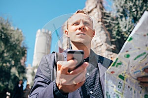 Tourist man try navigate himself with map and smartphone in unknown city