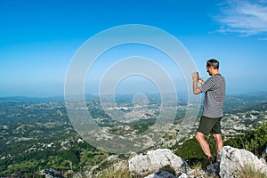 Tourist man on viewpoint at top of Jezerski mountain, near Njegos mausoleum at Cetinje city background. Lovcen National Park.