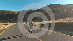 Tourist man walking on center of mountain road on sunset. Joyful guy having adventure in mountains.