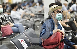 Tourist man with wearing medical mask and social distancing during waiting flight at gate