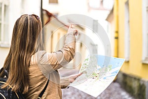 Tourist with map in the city. Woman pointing at right direction